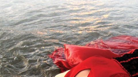 Elizabeth Lezama-Ruiz se sumerge en el Lago Michigan con su vestido rojo de Quinceañera durante su sesión fotografía después de su fiesta.