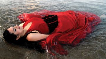 Elizabeth Lezama-Ruiz se sumerge en el Lago Michigan con su vestido rojo de Quinceañera durante su sesión fotografía después de su fiesta.
