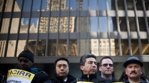 El concejal mexicoamericano Daniel Solís (c) sostiene una pancarta junto a otros funcionarios públicos.