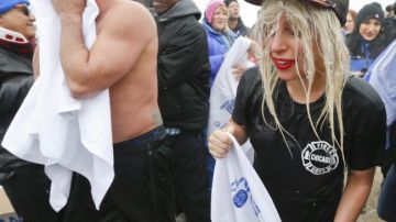 La cantante estadounidense Lady Gaga (d) y su prometido el actor Taylor Kinney (L) salen del lago Michigan después de hacer la tradicional "zambullida del oso polar" en Chicago.