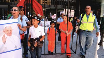 Vestidos con uniformes de reclusos color naranja, encadenados y encerrados en una cárcel simulada, un grupo de inmigrantes hizo una representación simbólica de las detenciones y separaciones de familias.
