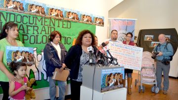 María Elena Orozco, con blusa verde, muestra un cartel a los reporteros  junto a la pequeña Jocelyn Ramírez, de cuatro años.