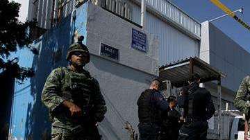 Elementos del Ejercito Mexicano y policías federales resguardan una calle.