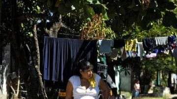 Mujer y niño junto a un grafiti del Barrio 18 en la colonia Valle del Sol en Apopa, El Salvador