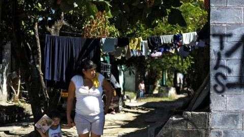 Mujer y niño junto a un grafiti del Barrio 18 en la colonia Valle del Sol en Apopa, El Salvador
