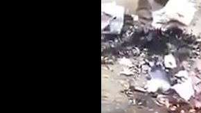 El hombre, rodeado de otros, descuartiza al perro.