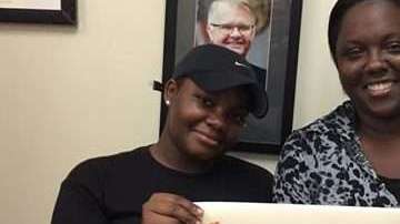 Triticia Crowley (i) muestra el cheque del  premio de la Lotería de Florida.