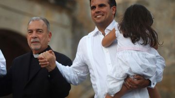 Monseñor Wilfredo Peña y Rosselló con su hija en brazos durante el acto