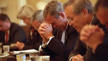 El presidente George W. Bush baja su cabeza en señal de solemnidad en medio de una oración encabezada por el secretario de Defensa, Donald Rumsfeld, en una reunión de gabinete el 14 de septiembre de 2001.