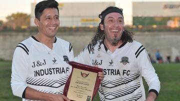 Ricardo Osorio (izquierda) recibe del también exprofesional Cosme Castro Vargas la placa de reconocimiento. (Javier Quiroz / La Raza)