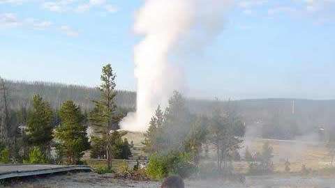 Un científico toma muestras en Ear Spring. Old Faithful se ve detrás.