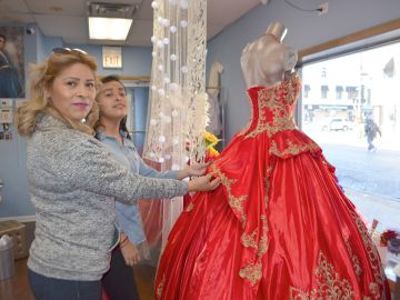 La jovencita Jessenia Sandoval junto a sus padres viendo invitaciones y vestidos de quinceañera en La Villita. (Belhú Sanabria / La Raza)