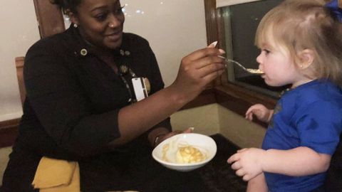 Camarera alimenta a niña para que su madre pueda cenar.