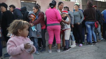 Migrantes esperan por comida en un albergue en Tijuana.