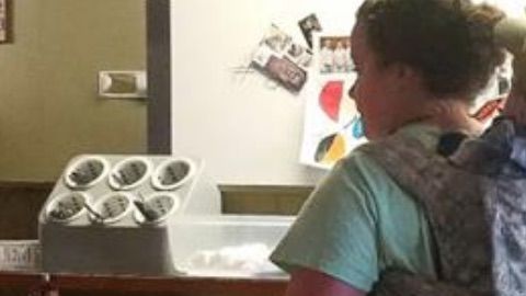 Una mesera lleva a su bebé a la espalda.