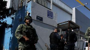 Elementos del Ejercito Mexicano y policías federales resguardan una calle.
