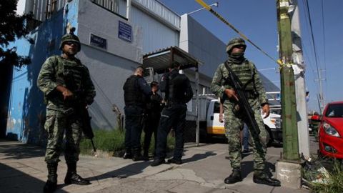 Elementos del Ejercito Mexicano y policías federales resguardan una calle.