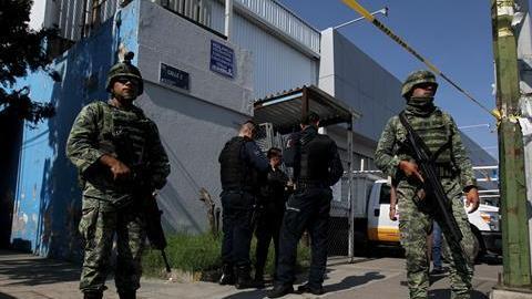Elementos del Ejercito Mexicano y policías federales resguardan una calle.