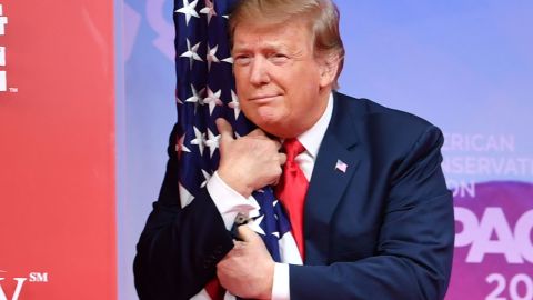 TOPSHOT - US President Donald Trump hugs the US flag as he arrives to speak at the annual Conservative Political Action Conference (CPAC) in National Harbor, Maryland, on March 2, 2019. (Photo by NICHOLAS KAMM / AFP) / ALTERNATIVE CROP        (Photo credit should read NICHOLAS KAMM/AFP/Getty Images)