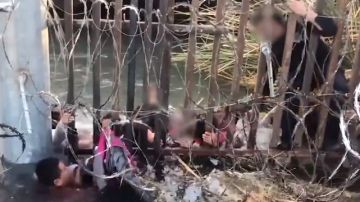 Uno de los video se ve a los inmigrantes cruzando por un río entre alambres de púas.