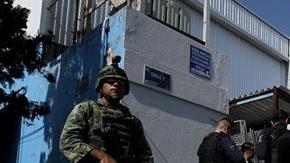 Elementos del Ejercito Mexicano y policías federales resguardan una calle.