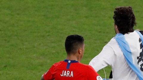 Gonzalo Jara de Chile traba a un aficionado que invadió el campo, durante el partido Chile-Uruguay de la Copa América.
