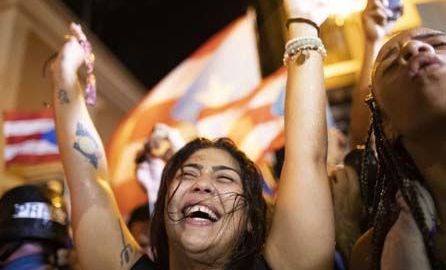 Una joven celebra la salida del gobernador de Puerto Rico, Ricardo Rosselló, en el exterior de La Fortaleza.