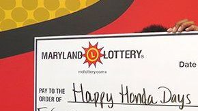 "Happy Honda Days" sostiene el cheque de su premio de lotería.