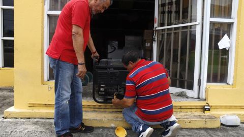 Personas preparan un generador de energía para una casa en Yabucoa, Puerto Rico.