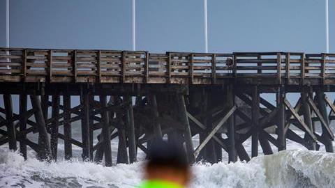 Personas miran el oleaje desde Main Street Pier de Daytona Beach, Florida,