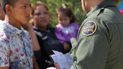 Esta fotografía de archivo muestra a una familia migrante conversando con un agente estadounidense.