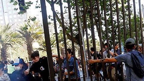 Manifestantes sacan una reja este lunes para ser lanzada a una barricada en el centro de la capital, sector Plaza Italia.