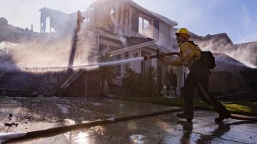 Bomberos apagan el fuego en una casa cerca de Santa Clarita en California.