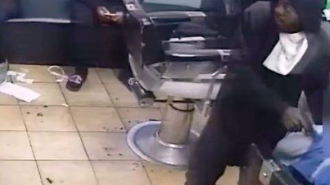 El ladrón apuntando a la victima en la silla del barbero