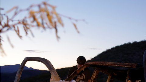 Los familiares de las víctimas frente a uno de los vehículos que resultó incendiado en la emboscada.