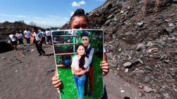 Una mujer sostiene la foto de unos familiares que murieron por la erupción del Volcán de Fuego el 3 de junio de 2018.