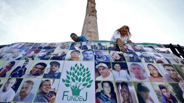 Miembros de la asociación Familias Unidas por Nuestros desaparecidos Jalisco preparan una pancarta con retratos de personas desaparecidas en Guadalajara.