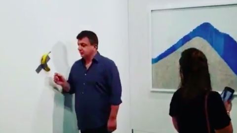 El momento cuando David Datuna llega a comer la obra de Maurizio Cattelan.