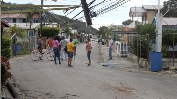 Unos residentes observan en la calle los daños causados por el temblor del lunes.