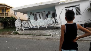 Un niño observa una casa dañada por uno de los temblores en Puerto Rico.