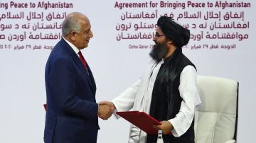 El representante especial de EEUU Zalmay Khalilzad, da la mano al cofundador del Talibán, Mullah Abdul Ghani Baradar.
