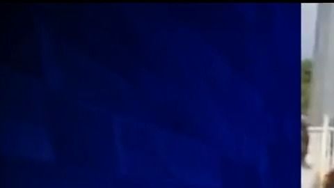 Momento del video en el que aparece la mujer entre los estudiantes y tocando la funda de su arma.