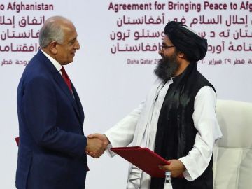 Zalmay Khalilzad da la mano al cofundador del Talibán, Mullah Abdul Ghani Baradar, durante la firma del acuerdo .