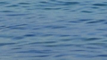 Tres mujeres sentadas en una orilla de una playa nudista de Australia.