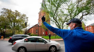 Annapolis (United States), 18/04/2020.- A counter protestor gestures to the vehicles of supporters of the group 'Reopen Maryland' as they fill Church Circle to protest the state's on-going stay-at-home order due to the coronavirus COVID-19 pandemic in Annapolis, Maryland, USA, 18 April 2020. In response to state shutdowns over the virus, the US President stated he would authorize governors to reopen their states on their own timelines. (Protestas, Abierto, Estados Unidos) EFE/EPA/JIM LO SCALZO