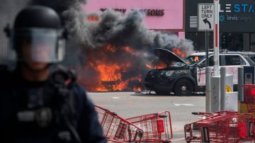 Autos de la Policía arden durante los disturbios en el oeste de L.A.