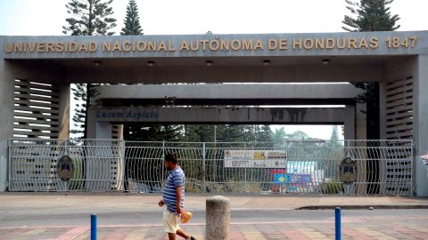 AME7017. TEGUCIGALPA (HONDURAS), 01/05/2020.- Un hombre camina este viernes frente al portón principal de la Universidad Nacional Autónoma de Honduras, que se encuentra cerrada dadas las medidas contra la pandemia COVID-19, en Tegucigalpa (Honduras). El cierre de los centros educativos y el confinamiento por el coronavirus han provocado que al menos la mitad de los 2,9 millones de alumnos en Honduras no reciba clases, principalmente los del área rural, porque no tienen un ordenador, ni internet, para llevar las clases a distancia. EFE/Gustavo Amador