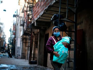 Una mujer  camina con su bebé  por una calle de la Villa 31, una de las más peligrosas de  Buenos Aires.