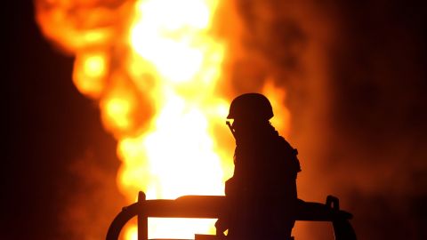 A Mexican soldier stands guard while workers of the Mexican state-owned oil company Pemex and local firefighters work to control a fire believed to have started in a pipeline due to fuel-theft activity in the community of San Sebastianito, in Tlajomulco, jalisco state, Mexico, on April 3, 2018. - Fuel theft is becoming more common every year in Mexico as drug cartels and other gangs diversify their illegal activities. Thousands of illegal taps were discovered in pipelines in recent years. Illegal taps have caused environmental disasters and deaths in the past. (Photo by ULISES RUIZ / AFP)        (Photo credit should read ULISES RUIZ/AFP via Getty Images)