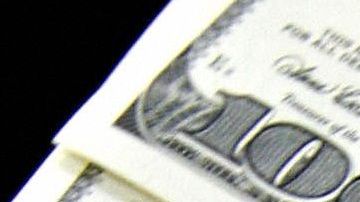 A money changer holds a wad of USD bills